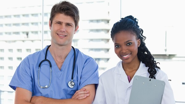 a male and female medical assistant wearing scrubs and smiling